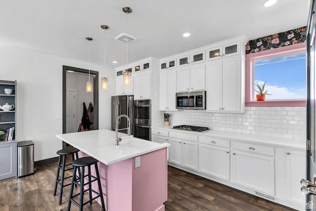 11386 S New Bern Way S, Jordan, UT 84009 - kitchen featuring stainless steel appliances, decorative backsplash, dark wood finished floors, a kitchen breakfast bar, and white cabinets
