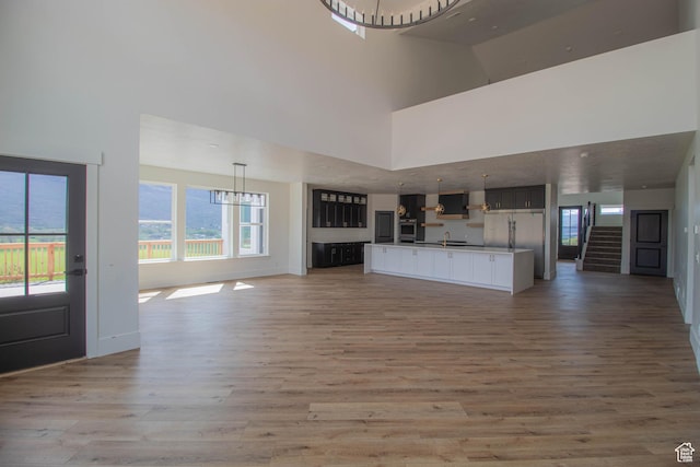 479 S 550 E, Wallsburg, UT 84082 - unfurnished living room featuring a towering ceiling, light wood-style flooring, a sink, baseboards, and stairs