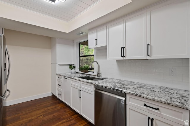 kitchen featuring appliances with stainless steel finishes, a sink, baseboards, and decorative backsplash