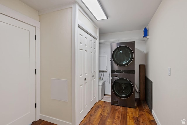 laundry area with stacked washing machine and dryer, wood finished floors, and baseboards