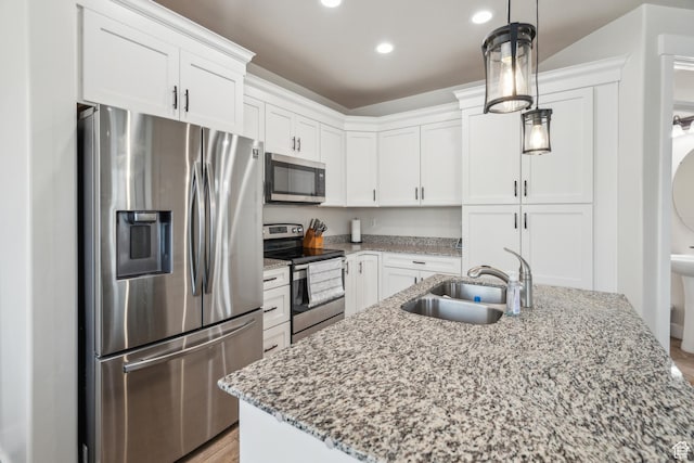 kitchen featuring appliances with stainless steel finishes, a sink, white cabinetry, light stone counters, and hanging light fixtures