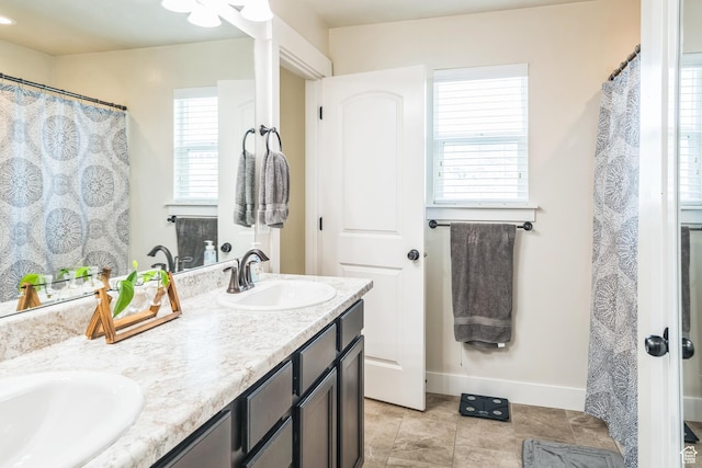 bathroom with double vanity, baseboards, and tile patterned flooring