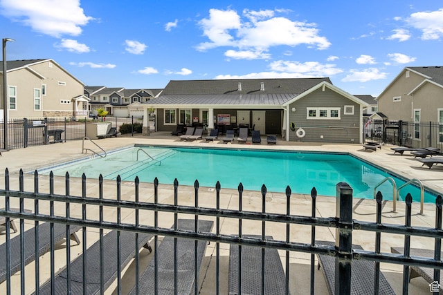 community pool featuring fence, a patio area, and a residential view