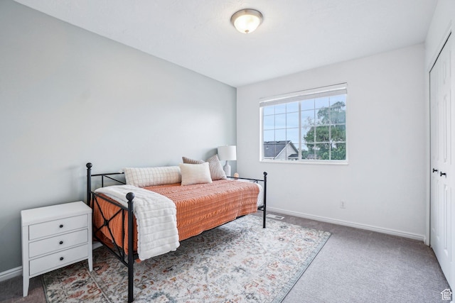 carpeted bedroom with baseboards and a closet