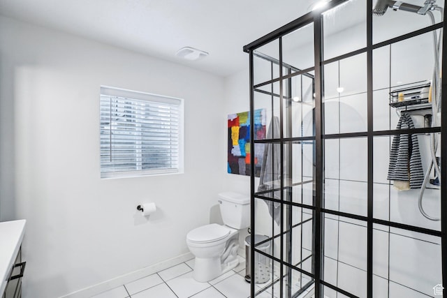 bathroom featuring toilet, tile patterned floors, baseboards, and a tile shower