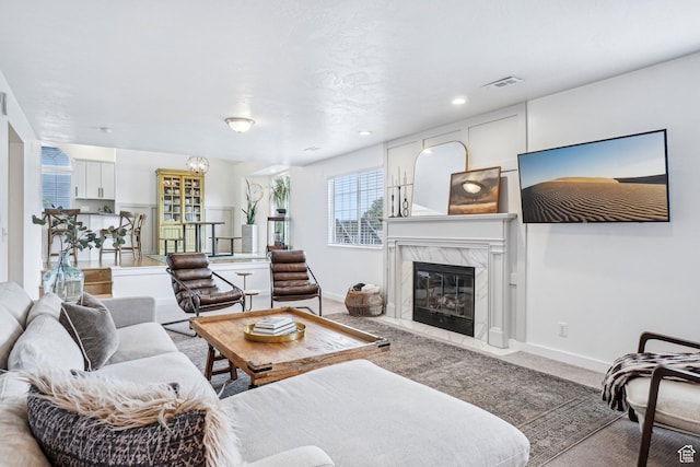 carpeted living room with a high end fireplace, baseboards, and recessed lighting