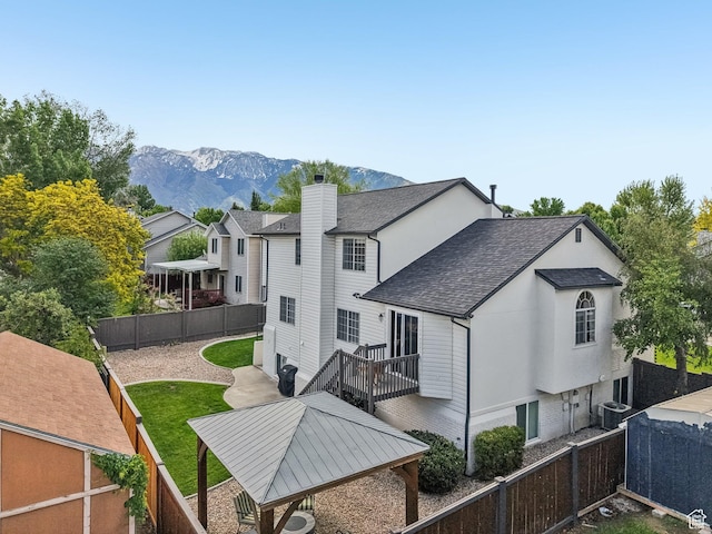back of property with roof with shingles, a fenced backyard, a mountain view, and central AC