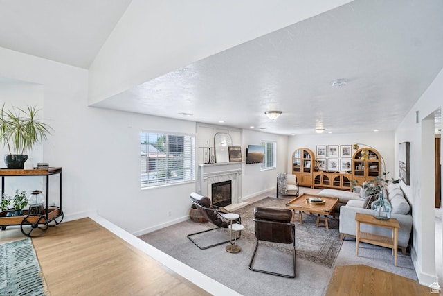 living area featuring a high end fireplace, baseboards, and light wood finished floors
