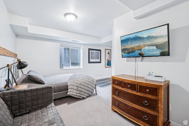 carpeted bedroom featuring a tray ceiling and baseboards