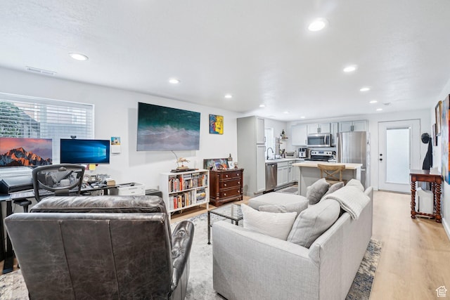living room with light wood-style flooring and recessed lighting
