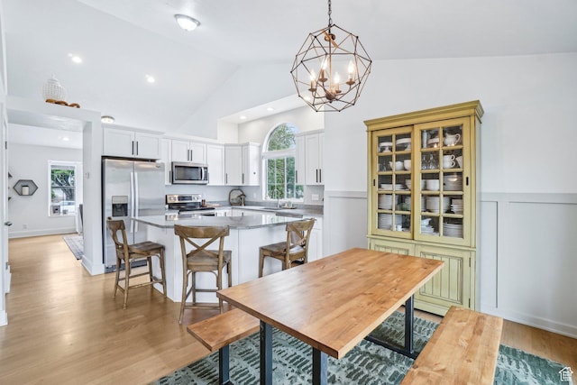 dining area featuring a chandelier, light wood-style floors, and high vaulted ceiling