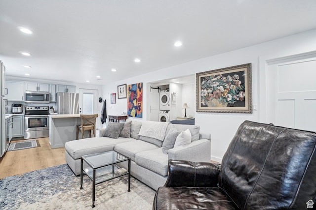 living room featuring stacked washer and clothes dryer, light wood-type flooring, and recessed lighting