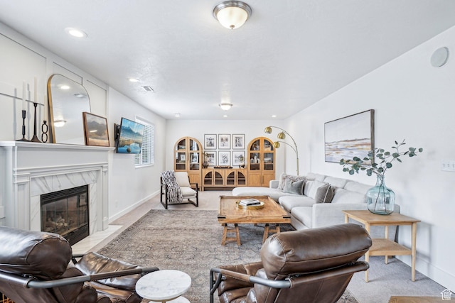carpeted living area with baseboards, a high end fireplace, and recessed lighting