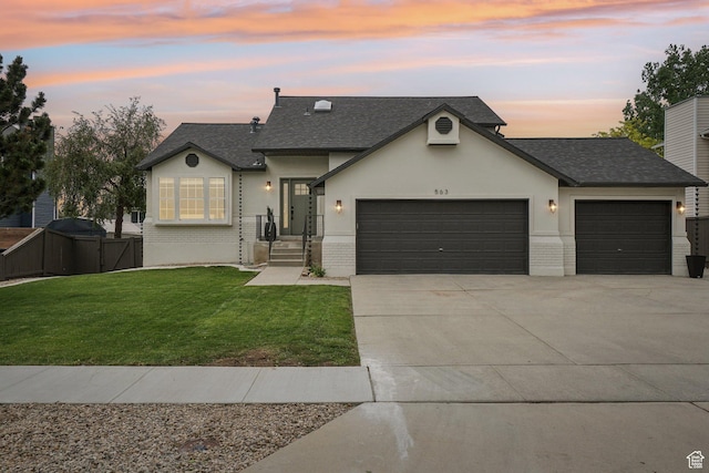 french country inspired facade with a garage, driveway, a shingled roof, and brick siding