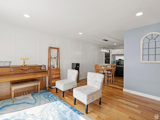 sitting room featuring a decorative wall, light wood-style flooring, and recessed lighting
