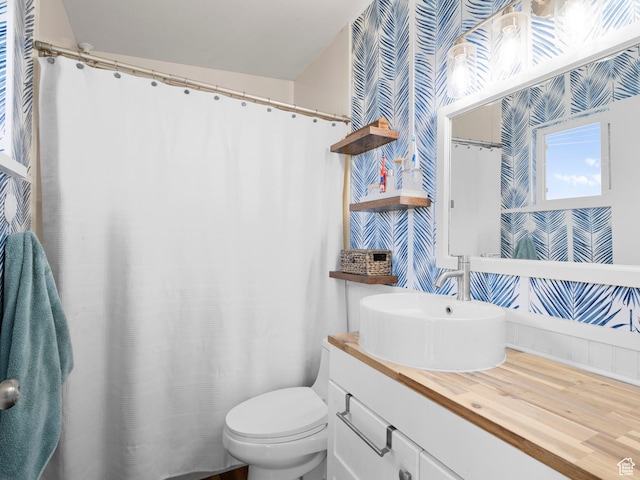 bathroom with wallpapered walls, toilet, and vanity