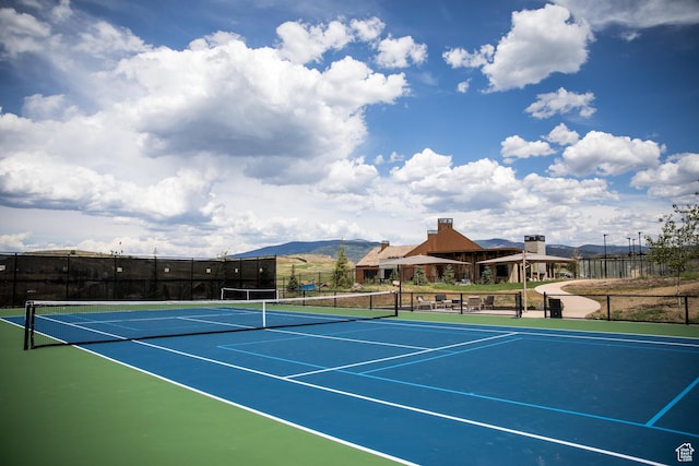 view of tennis court featuring fence, a mountain view, and community basketball court