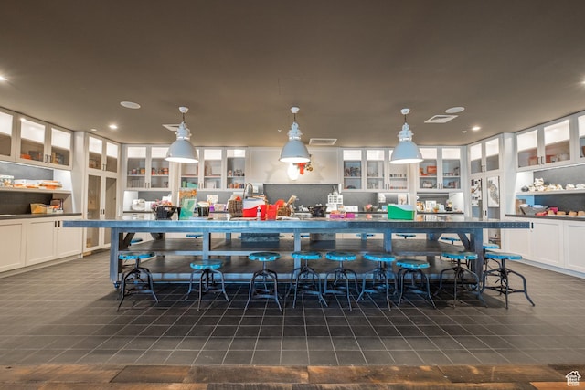 kitchen with white cabinetry, glass insert cabinets, decorative light fixtures, built in shelves, and recessed lighting