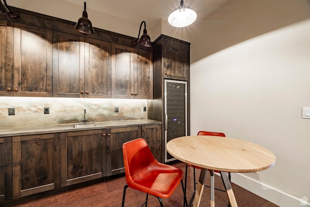 kitchen with tasteful backsplash, dark brown cabinets, a sink, beverage cooler, and light countertops