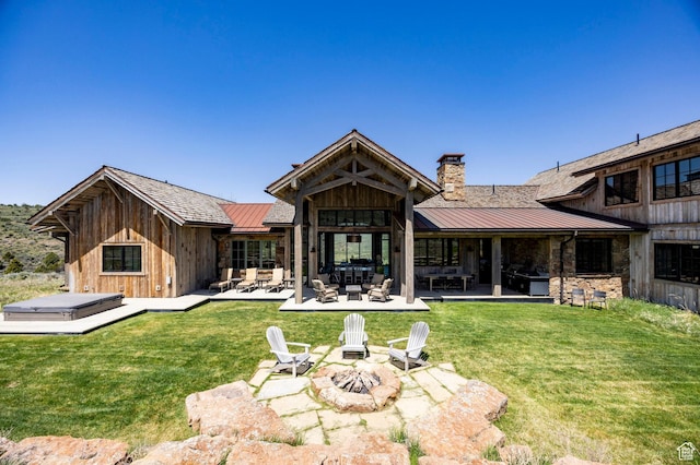 back of house with a standing seam roof, an outdoor living space with a fire pit, metal roof, and a chimney