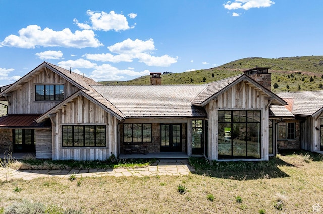 back of house with a chimney, french doors, a yard, and a mountain view