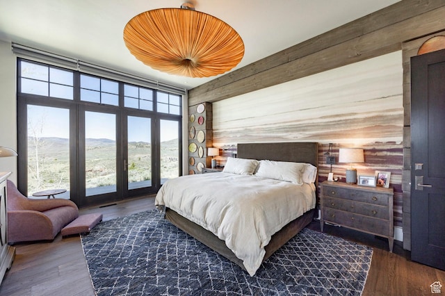 bedroom with wooden walls, a mountain view, and wood finished floors