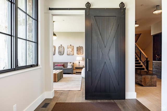 hallway featuring wood finished floors, a barn door, healthy amount of natural light, and stairs