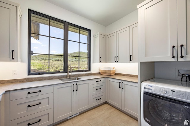 washroom featuring washer / dryer, cabinet space, and light tile patterned floors