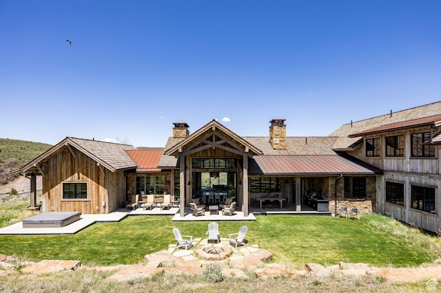 back of property with a standing seam roof, a chimney, metal roof, and a lawn