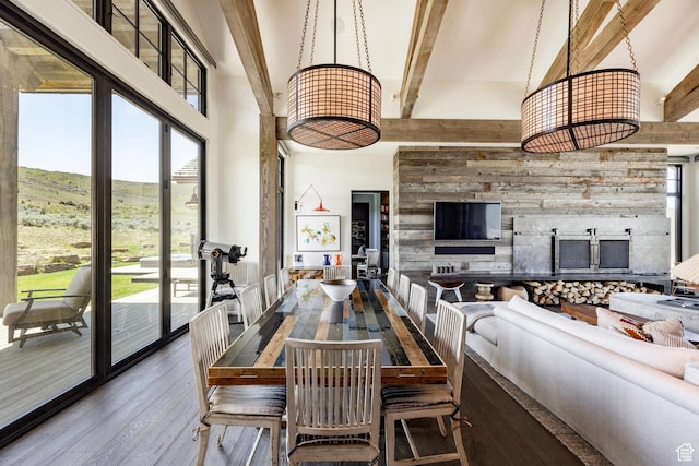 dining space featuring a towering ceiling, hardwood / wood-style flooring, beam ceiling, and a mountain view