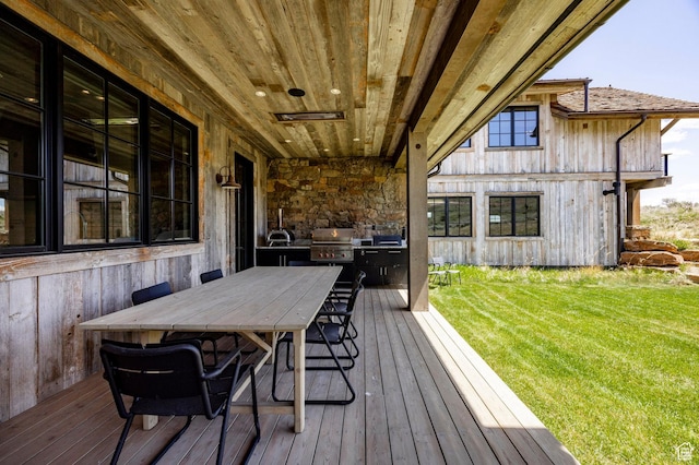 deck with a yard, a grill, outdoor dining space, and an outdoor kitchen
