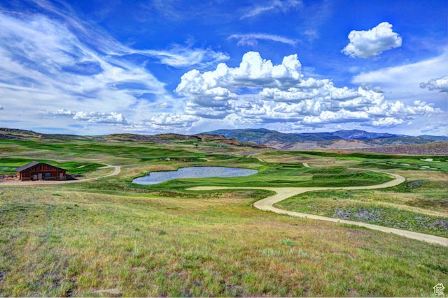 view of mountain backdrop featuring a nearby body of water and a local golf course
