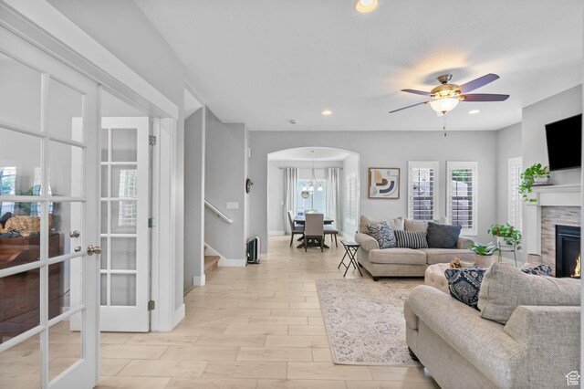 10426 S Kestrel Rise Rd, South Jordan, UT 84009 - living area featuring arched walkways, stairway, a warm lit fireplace, ceiling fan, and recessed lighting
