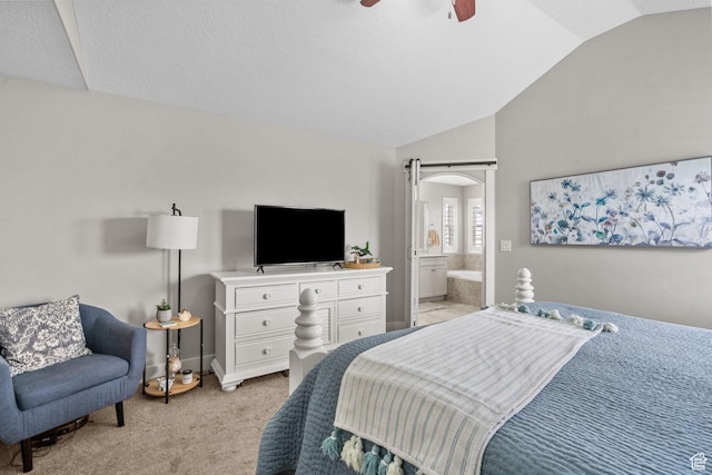 bedroom featuring vaulted ceiling, light colored carpet, connected bathroom, a ceiling fan, and arched walkways