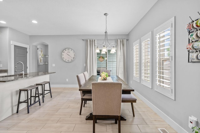 dining space featuring arched walkways, a chandelier, recessed lighting, and baseboards