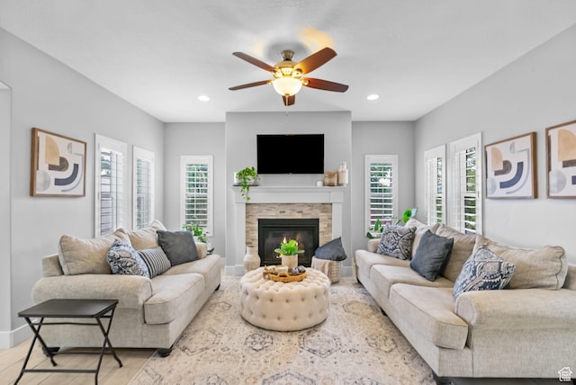 living area featuring plenty of natural light, ceiling fan, wood finished floors, a stone fireplace, and recessed lighting