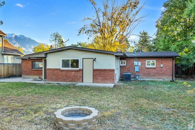 rear view of house featuring brick siding, central air condition unit, a mountain view, an outdoor fire pit, and a patio area