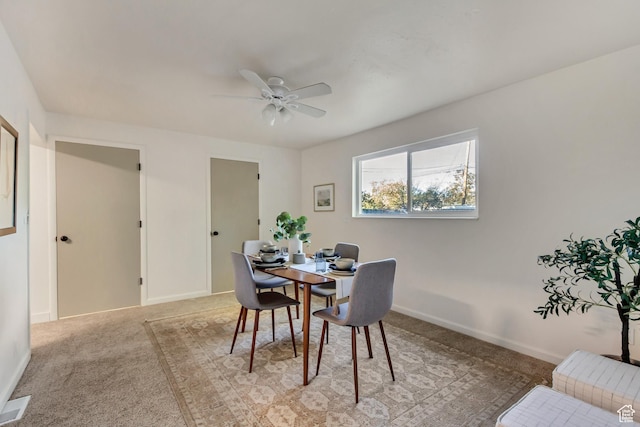 dining space featuring ceiling fan, light colored carpet, and baseboards