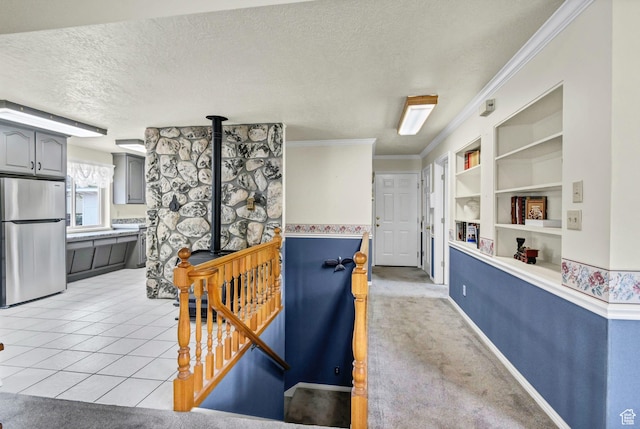 hall featuring a textured ceiling, built in features, crown molding, light tile patterned flooring, and baseboards