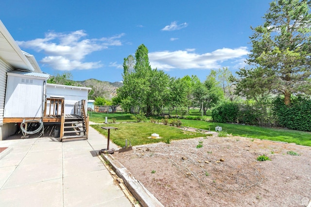 view of yard featuring a deck with mountain view, a vegetable garden, and a patio