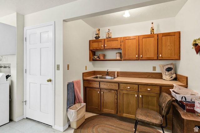 kitchen with a sink, brown cabinets, open shelves, washer / clothes dryer, and light countertops