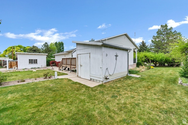 rear view of property with a yard, an outbuilding, and a patio area