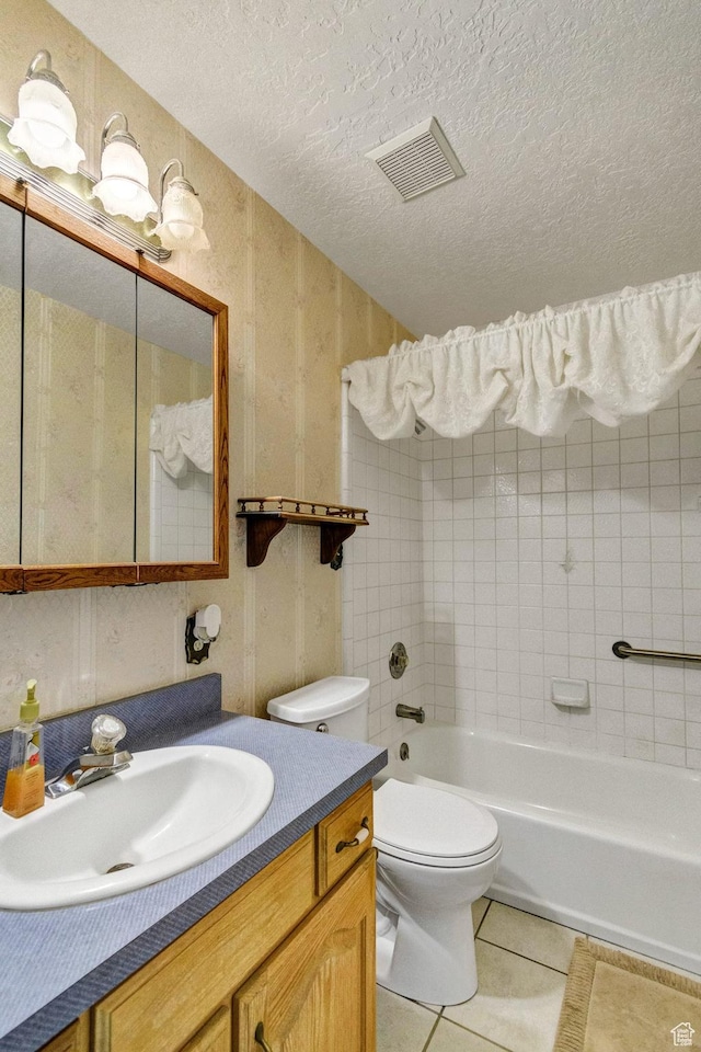 bathroom featuring tile patterned floors, toilet, vanity, a textured ceiling, and shower / washtub combination