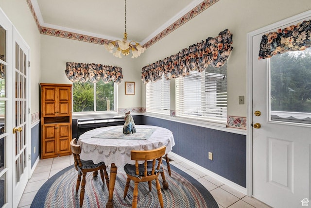 dining area featuring a chandelier, light tile patterned floors, and a wainscoted wall