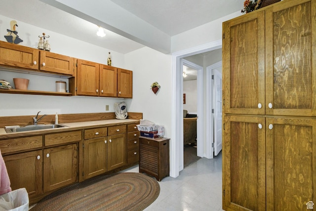 kitchen featuring a sink, brown cabinetry, open shelves, and light countertops