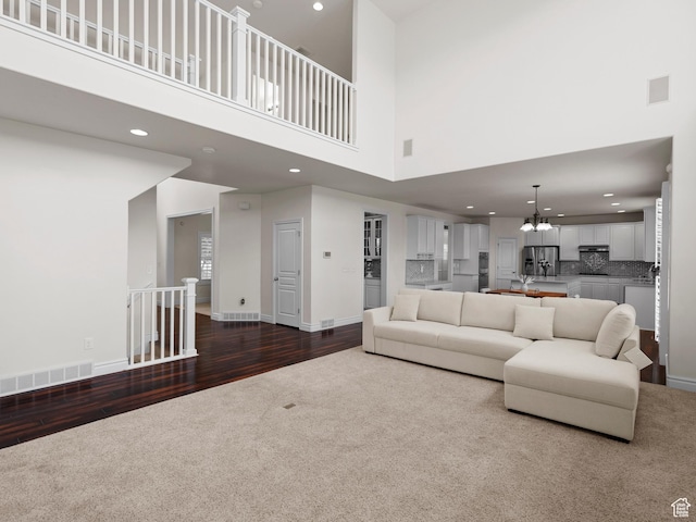3388 W Rocky Peak Way S, Jordan, UT 84095 - living area featuring dark colored carpet, a chandelier, a high ceiling, recessed lighting, and dark wood-style floors