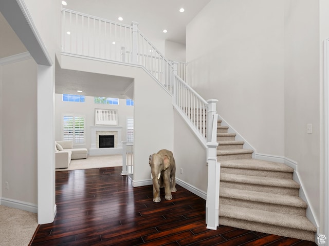 3388 W Rocky Peak Way S, Jordan, UT 84095 - stairway featuring wood finished floors, baseboards, a towering ceiling, recessed lighting, and a fireplace
