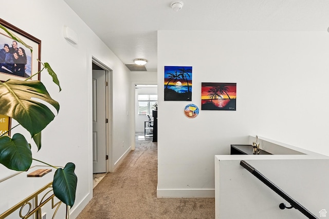 corridor with an upstairs landing, light colored carpet, and baseboards