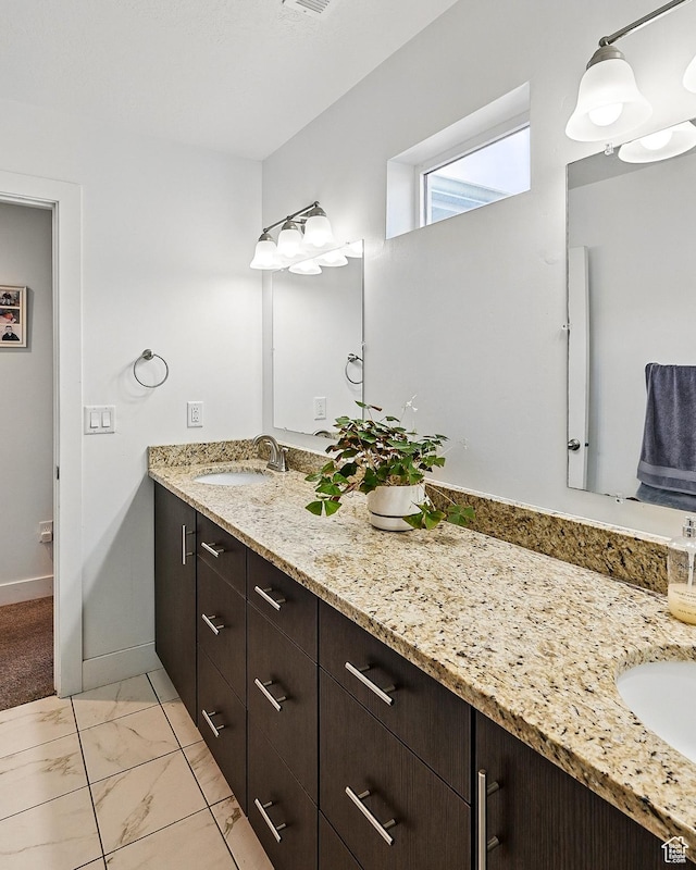 bathroom with vanity, marble finish floors, and baseboards