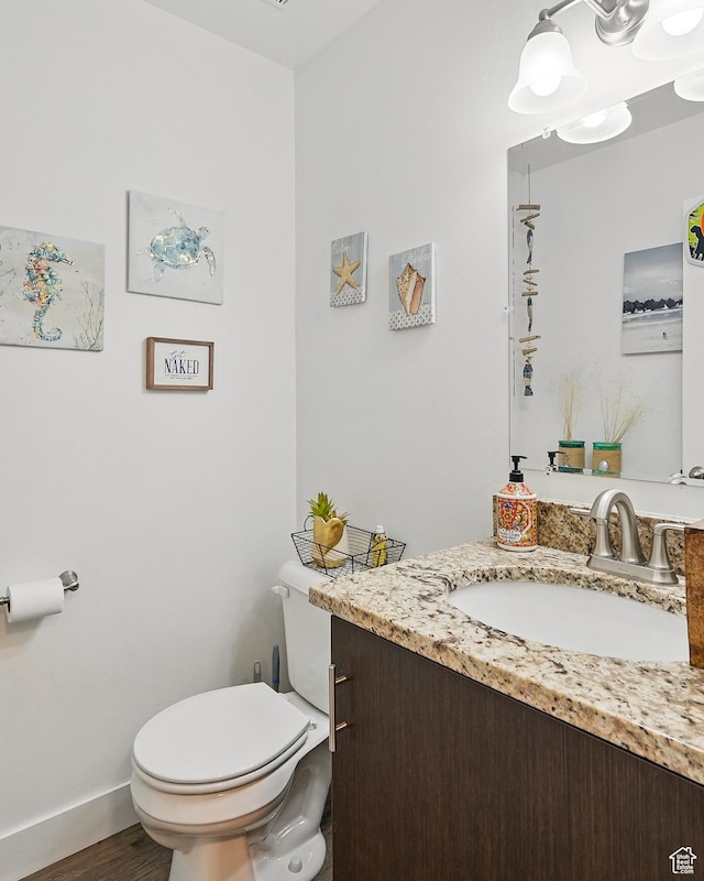 bathroom featuring toilet, vanity, wood finished floors, and baseboards